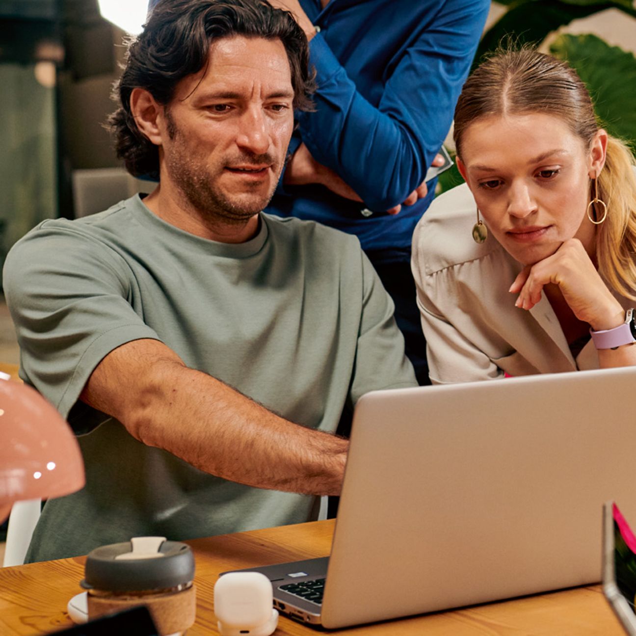 Two men and a woman are standing together at a table and discussing things with each other.