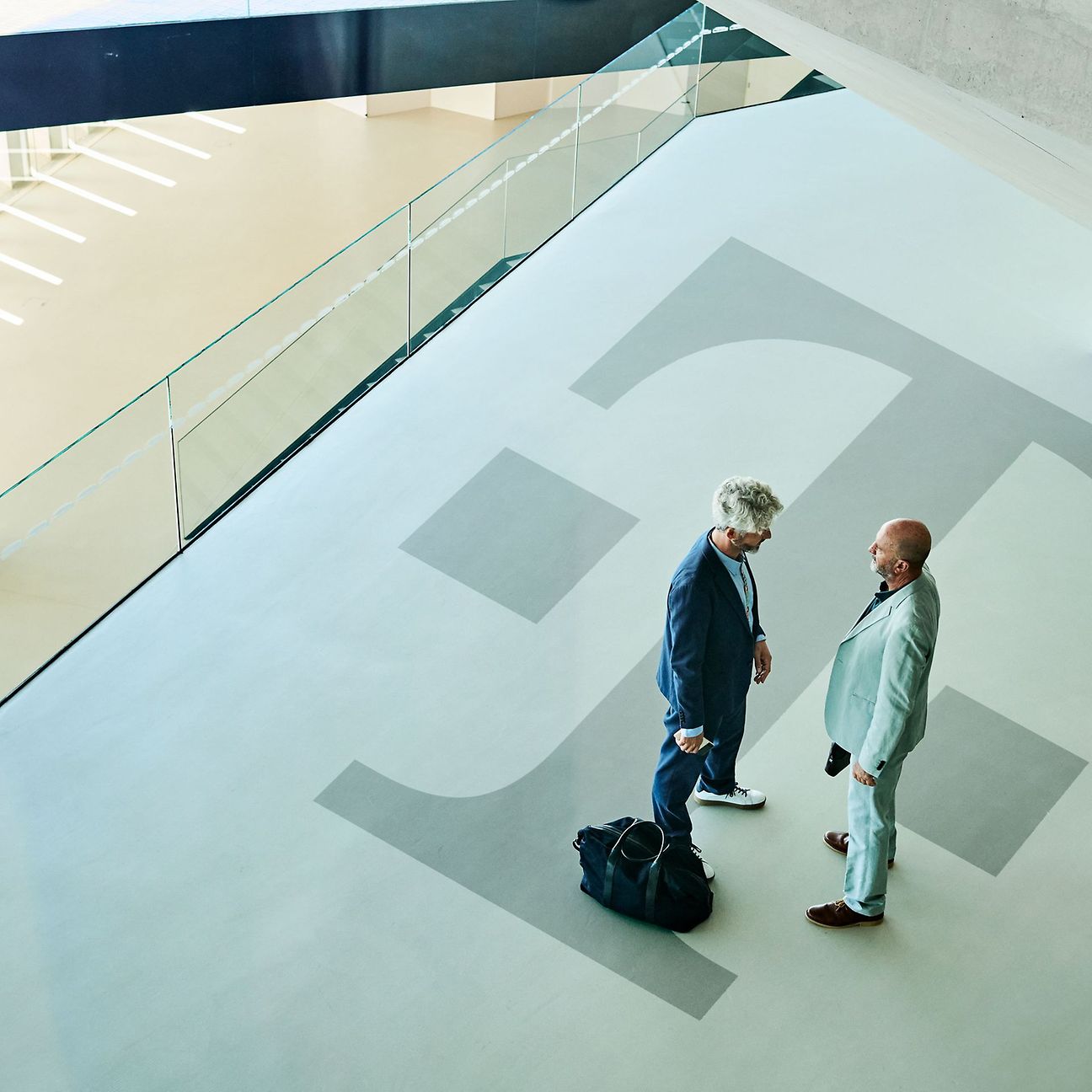 View from above of a wide corridor with a large Deutsche Telekom logo: Two people are talking