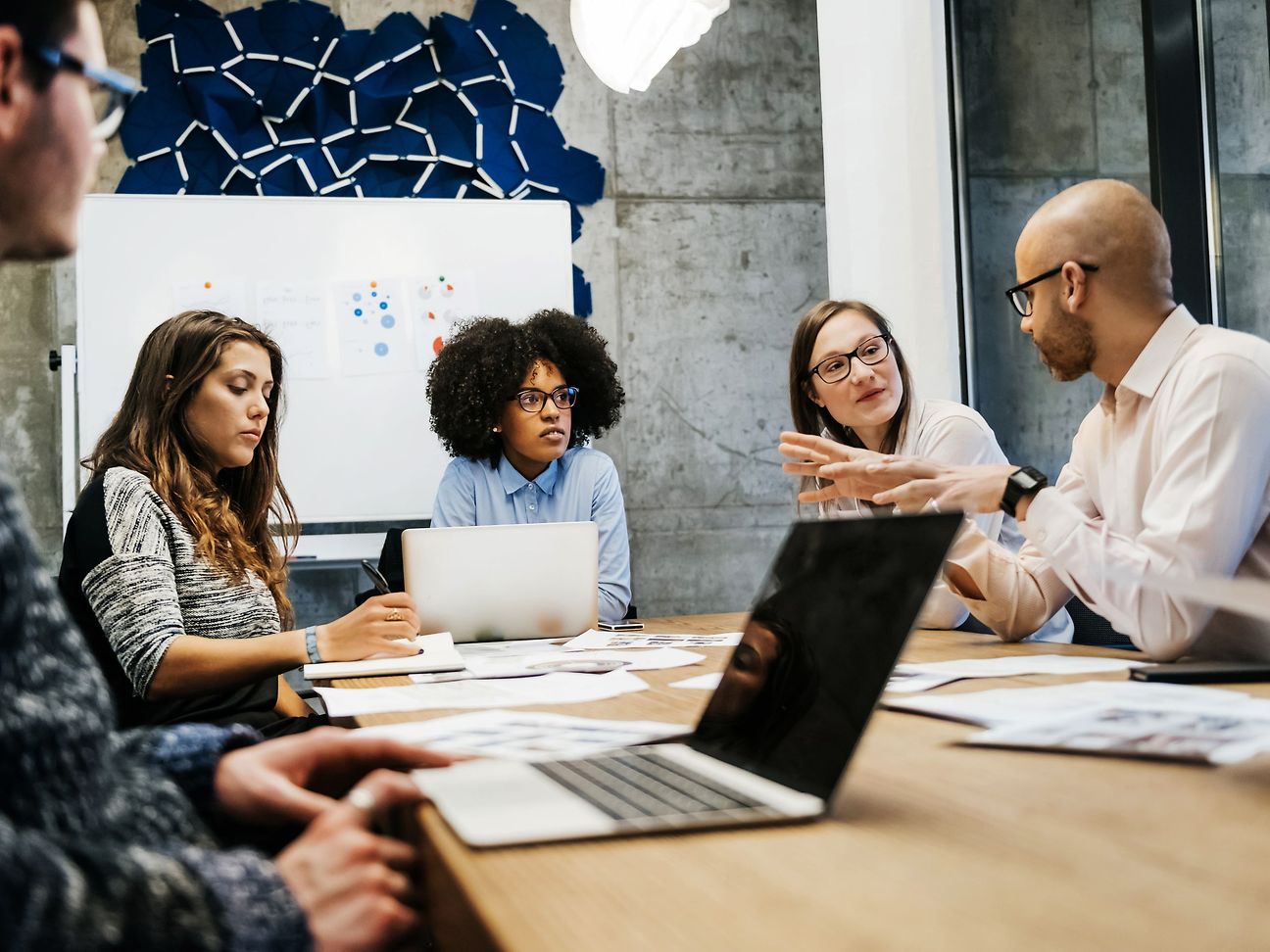 Several people are sitting at a table in a meeting room and are talking