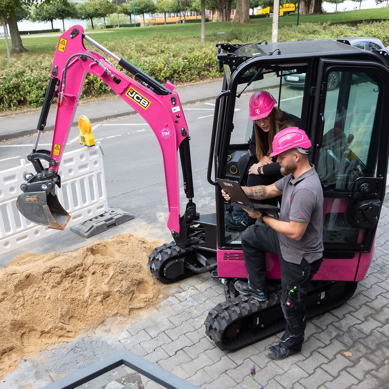 Magenta digger excavating a narrow trench next to a road to lay fiber-optic cable.