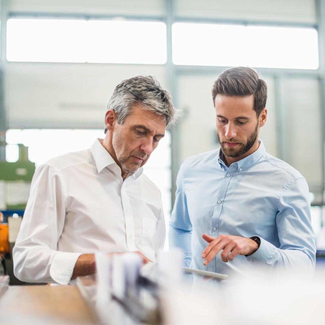 Two men in a modern office looking at a tablet