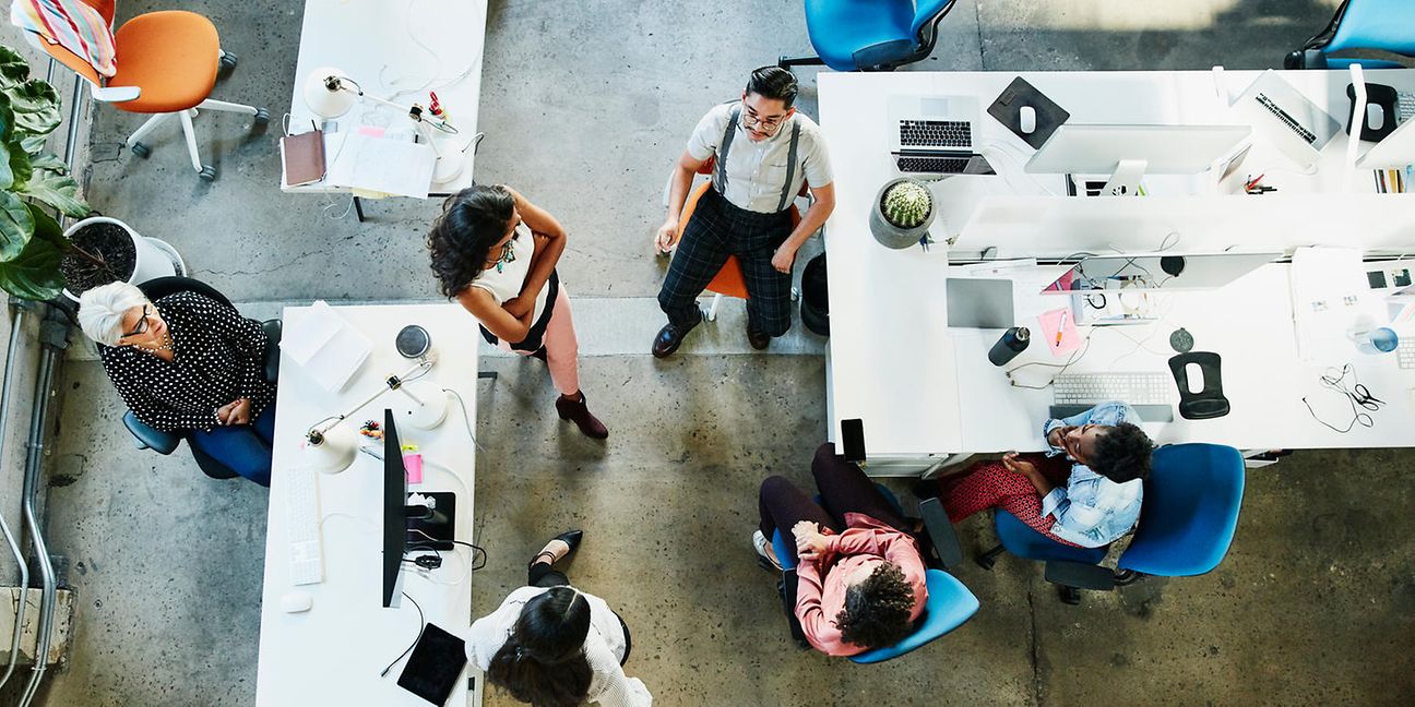 Several employees standing and sitting together in the office. View from above.