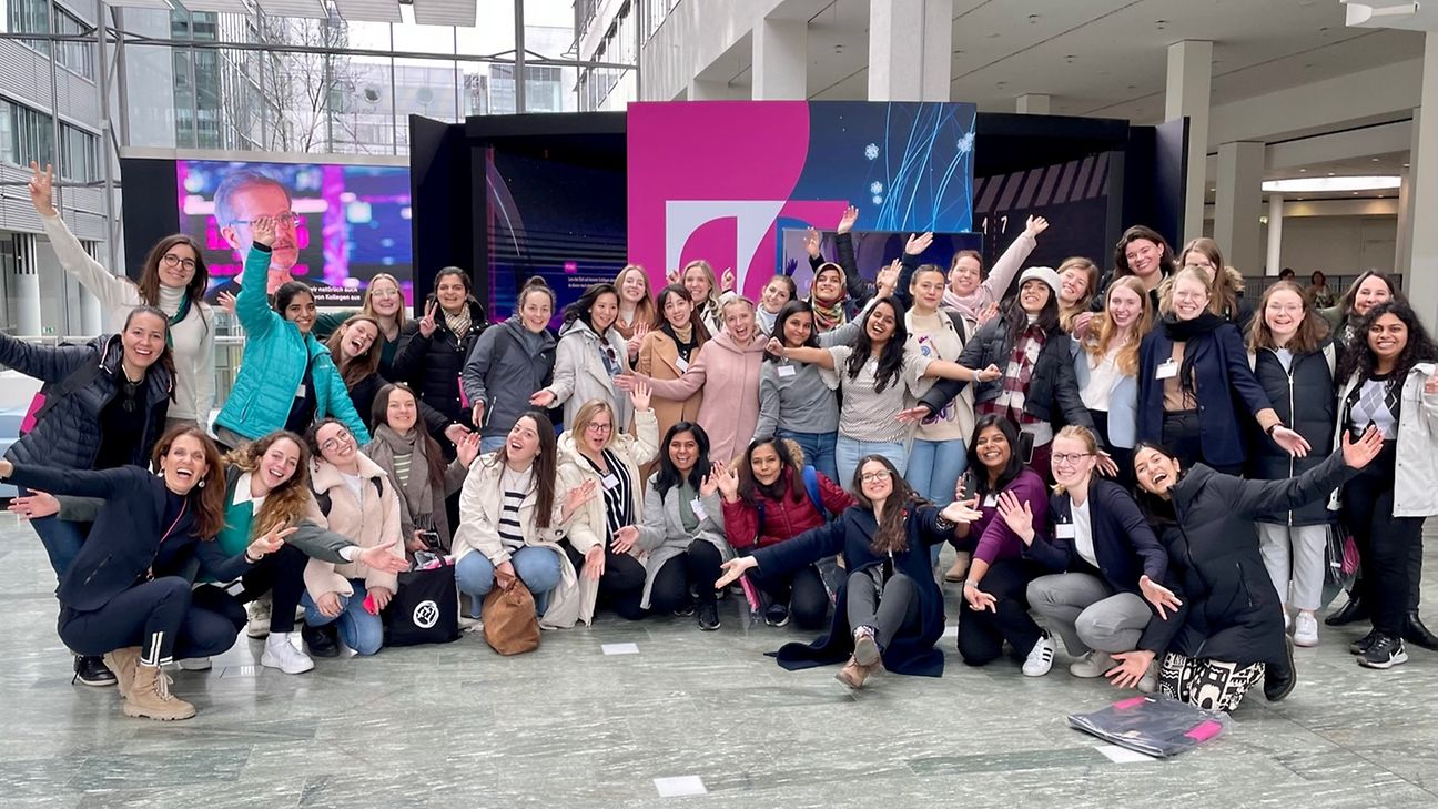 A large group of women looks into the camera, smiling and cheering.