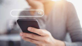 Woman holding smartphone. Search field seen above.