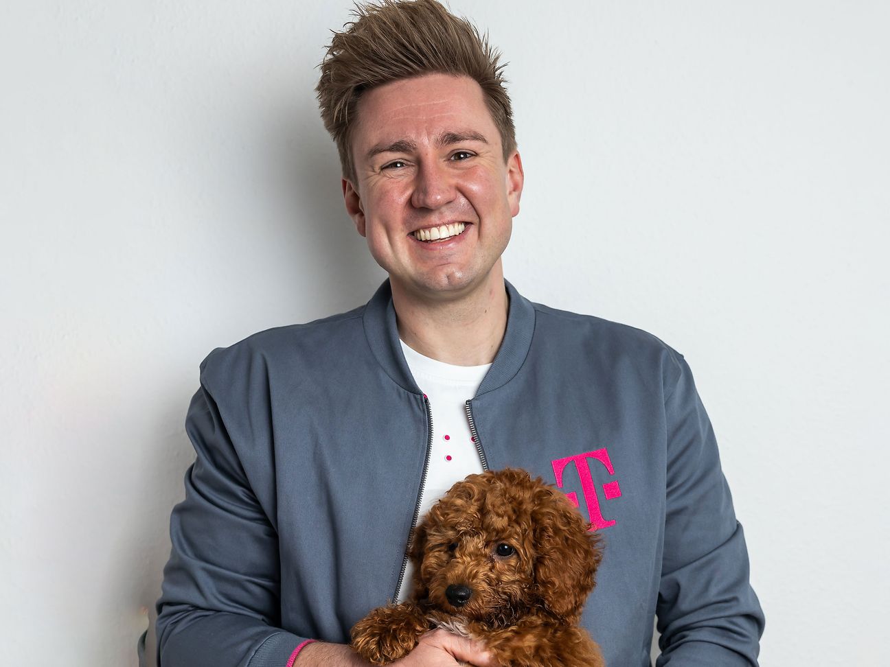  A young man holds a dog and smiles at the camera