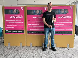 Csaba Almádi steht mit einem Blindenstock vor den Plakaten zum Wettbewerb.