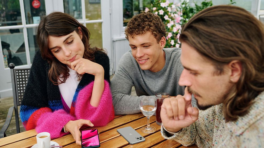 Three young people looking at a smartphone together and talking.