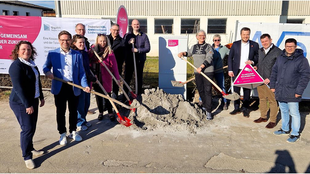 Gruppenfoto vor dem Bauernhof am neuen Netzverteiler, einige schaufeln Sand vom symbolischen Sandhaufen.