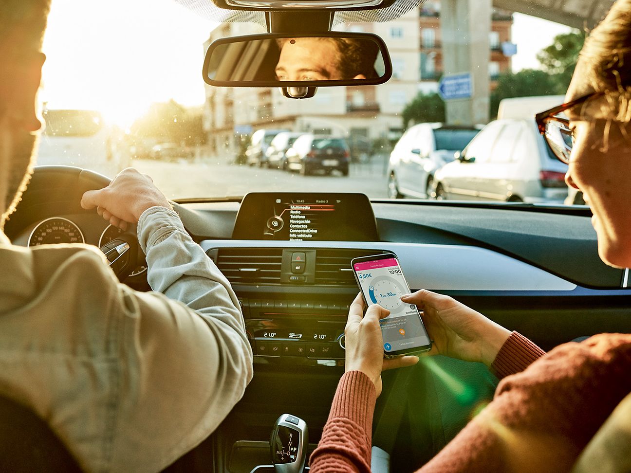 Frau mit Handy in der Hand im Auto.