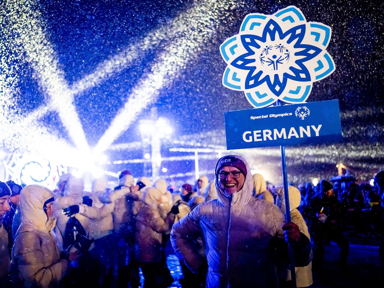 Mann mit Schild "Germany" bei Party zum Abschluss der Special Olympics Winterspiele.