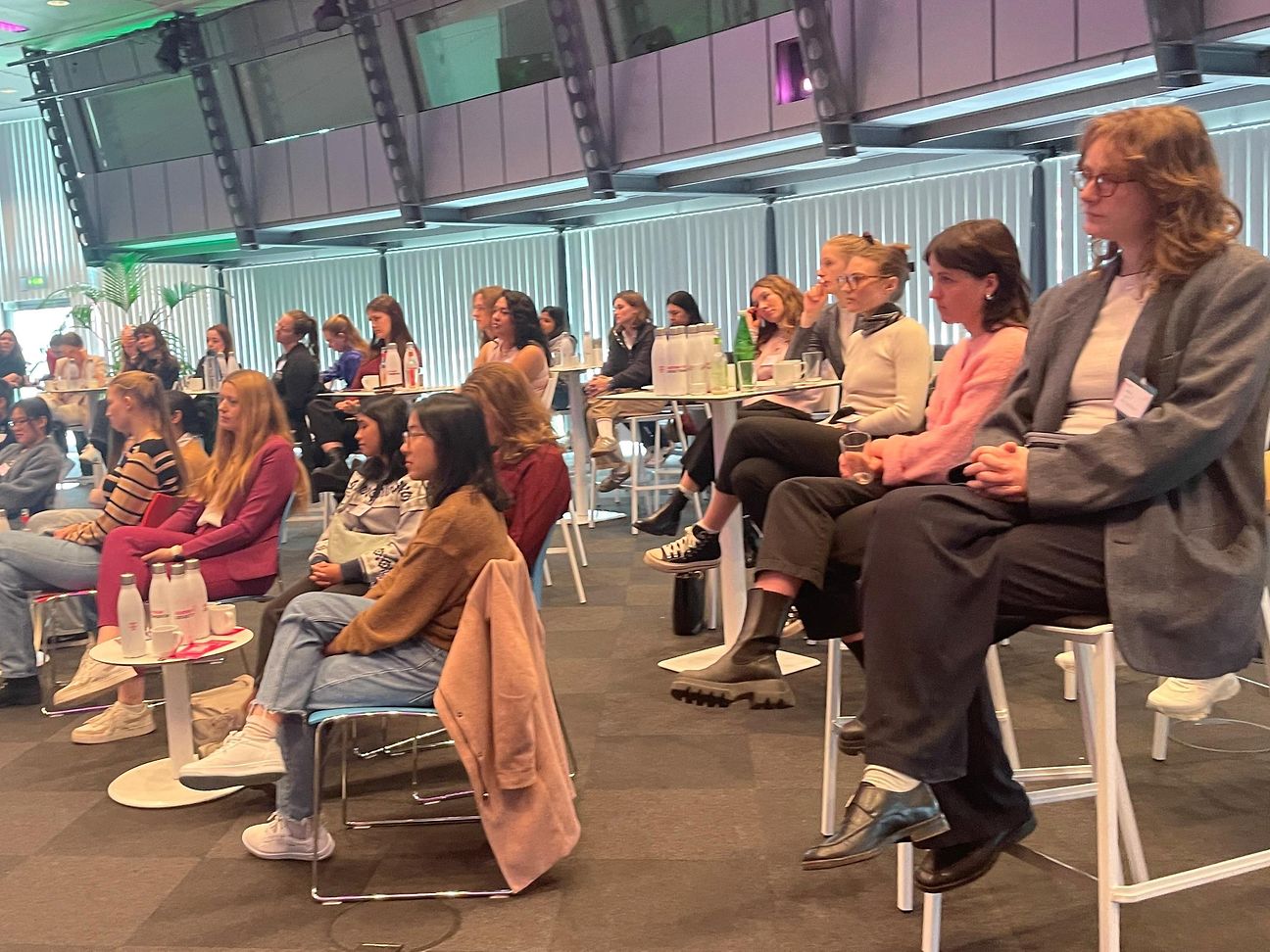 Young women sit in rows in a large Telekom room and follow the presentations