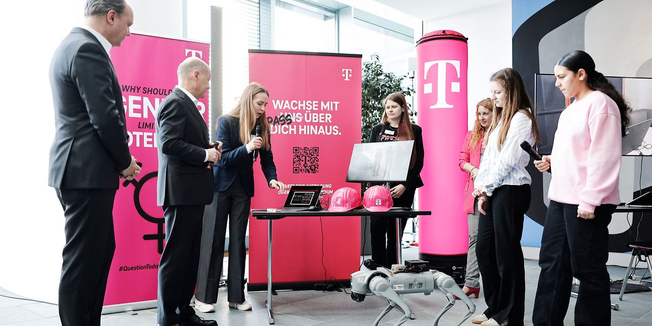 Eine Frau erklärt einer Gruppe von Menschen etwas an einem Laptop