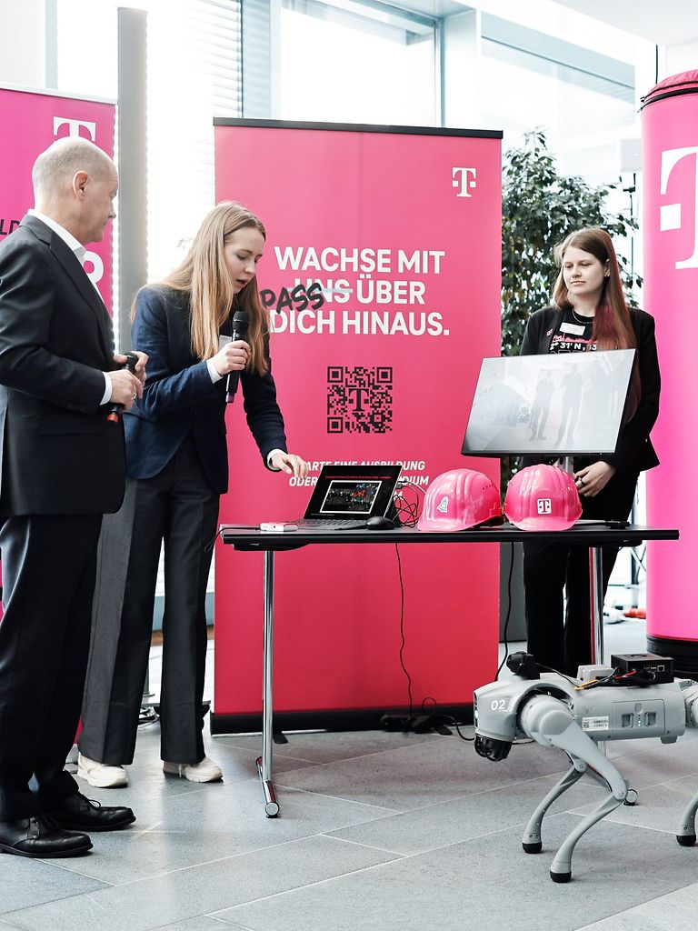Eine Frau erklärt einer Gruppe von Menschen etwas an einem Laptop