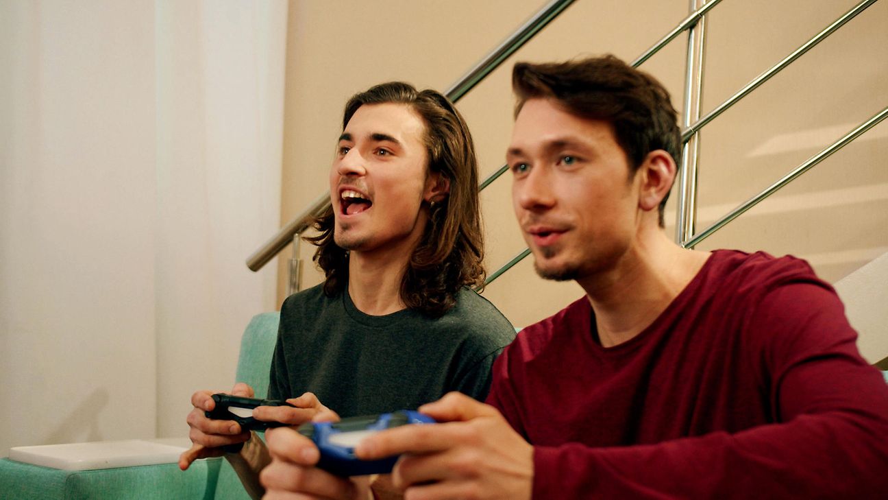Zwei junge Männer schauen spielen ein Spiel über die Console