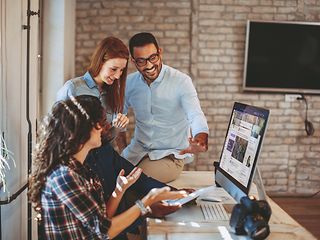 Four employees at a computer.