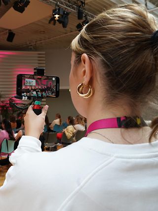 Volontärin filmt einen Vortrag mit der Handykamera. 