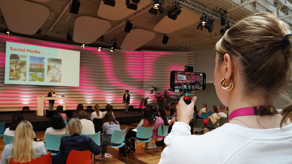 Volunteer films a lecture with her cell phone camera.