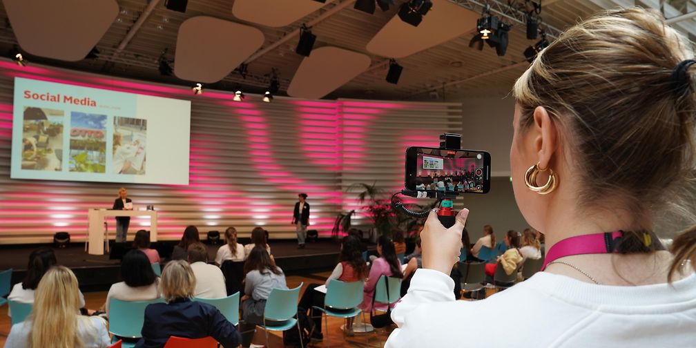 Volunteer films a lecture with her cell phone camera.