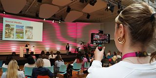 Volunteer films a lecture with her cell phone camera.