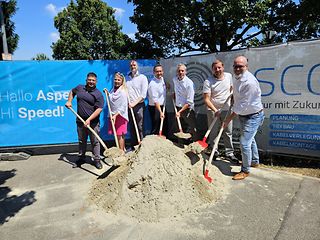 Der Bürgermeister von Asperg und die Vertreter von Telekom, SWLB und Zweckverband vor Sandhaufen.