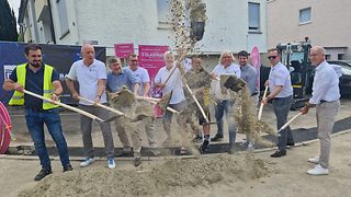 Alle Beteiligten werfen mit einer Schaufel Sand in die Höhe