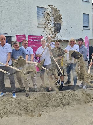 Alle Beteiligten werfen mit einer Schaufel Sand in die Höhe