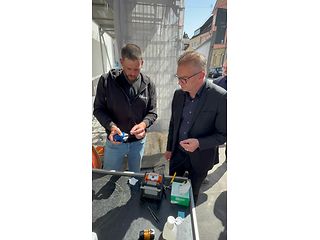 Ein Mitarbeiter der Telekom steht mit Dr. Möser am Spleißtisch und erklärt ihm die Technik