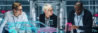 Drei Menschen arbeiten an einem digitalen Modell eines Autos.