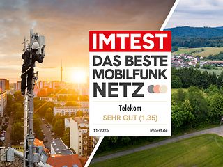 Techniker auf einem Mobilfunkmast mit Blick über eine Stadt bei Sonnenuntergang und Sendemast