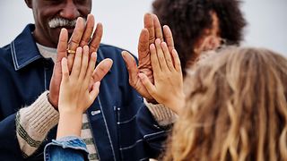 Two people clap hands, symbolizing unity, trust, and collaboration.