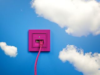 A pink outlet on a blue wall with clouds