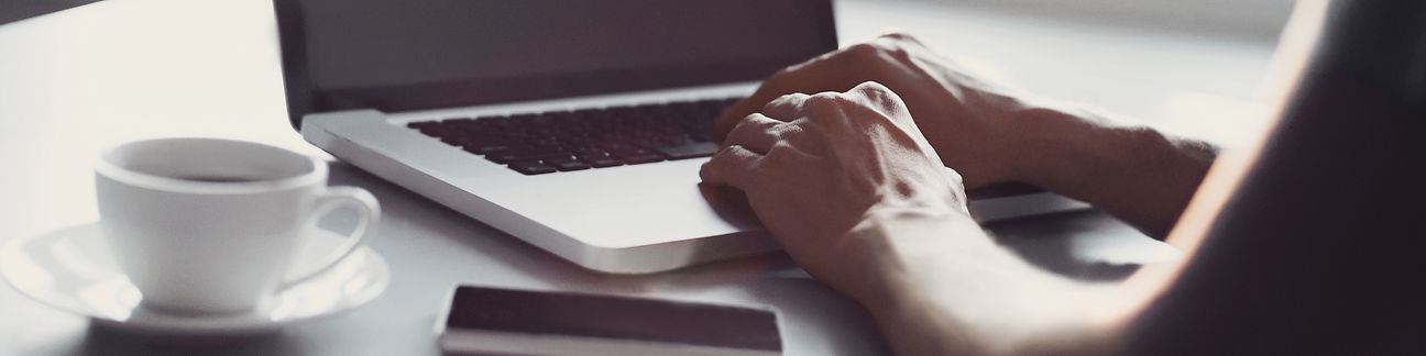 Laptop, Handy und Kaffeetasse auf dem Tisch