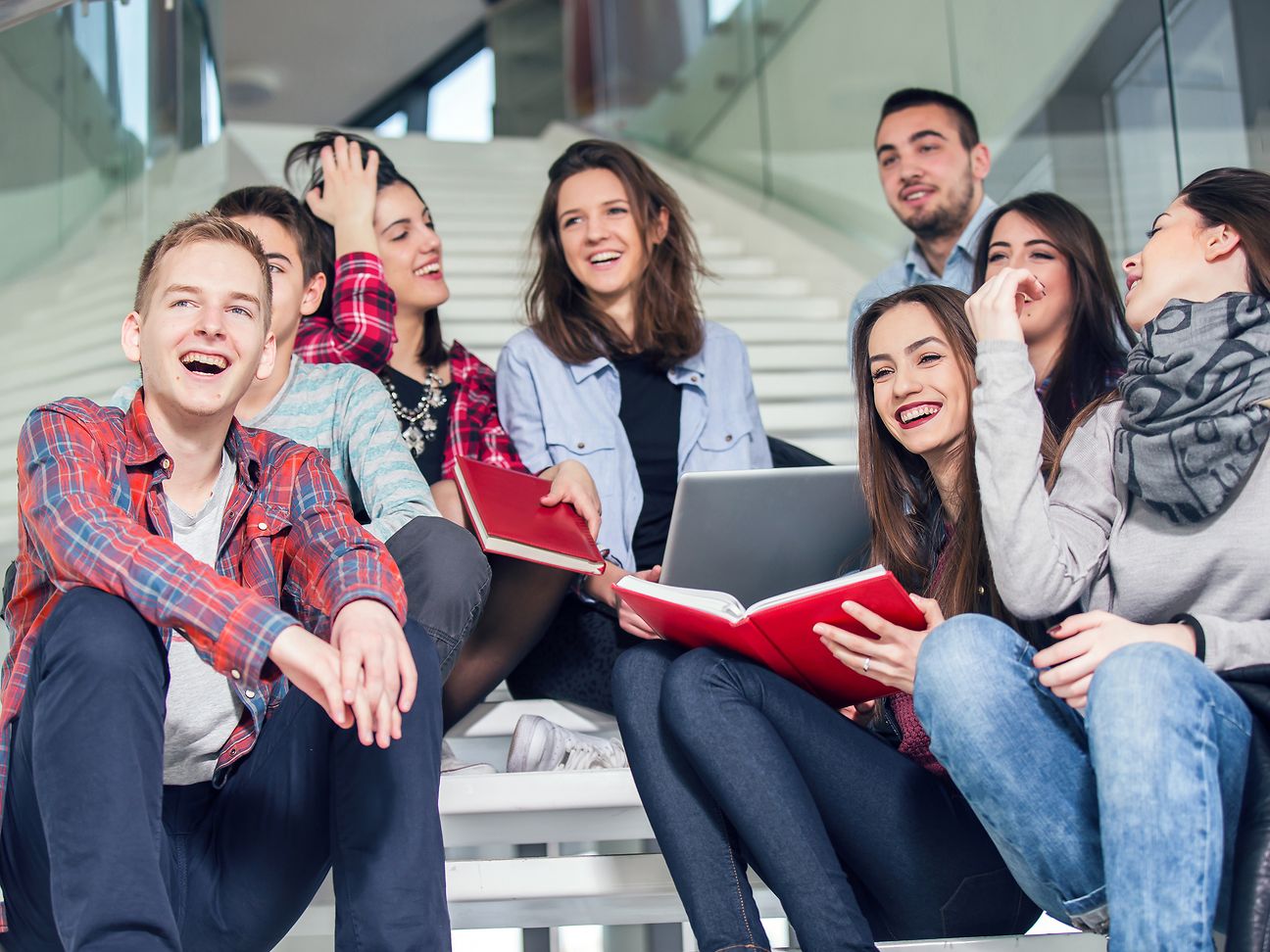 Schüler sitzen mit Laptop und Büchern auf Treppe