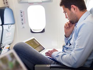 Inflight: Man sitting in the plane on laptop