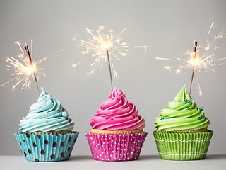 Three colorful cupcakes with sparklers