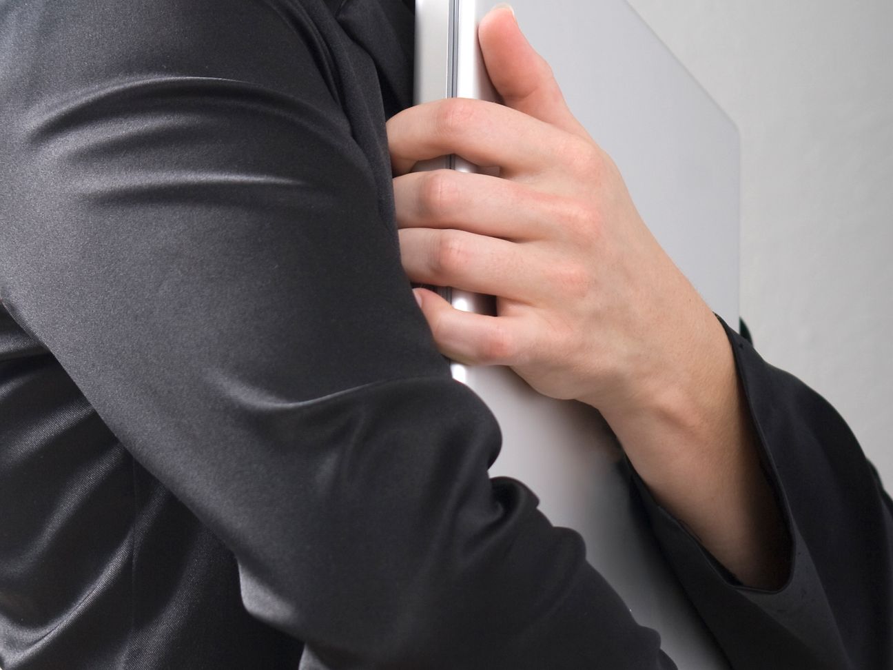 Ein Mann hält seine Arme schützend um ein Laptop.