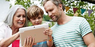 Großmutter, Vater und Sohn am Tablet-Computer.