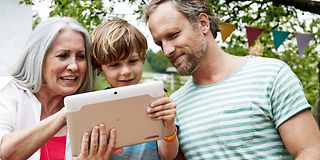 Grandmother, father and son looking at tablet computer.