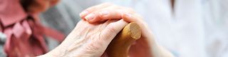 Younger hands hold the ones of an older woman