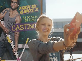 Clara Heins in front of the movie poster of „Fack Ju Göhte 2“.