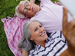 Älteres Paar liegt auf einer Picknickdecke. 