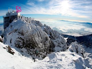Snow-.covered mountain with Restaurantbuilding on top, antennas to be seen.