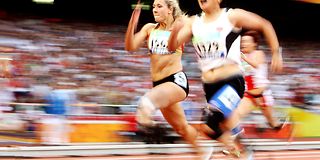 Drei Sportlerinnen mit Beinprothesen sprinten über Stadionbahn.