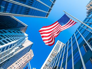 Symbolfoto mit US Flagge vor blauem Himmel