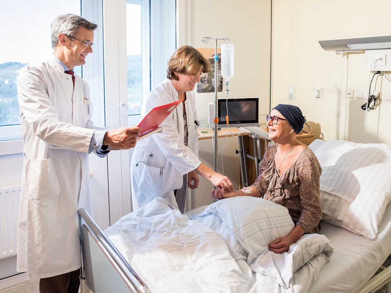 Zwei Ärzte am Krankenhausbett einer Patientin.