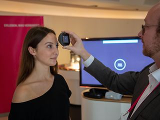 Henning Koch (r.) untersucht Alexandra Wegner (beide <nobr>T-Systems</nobr>) mit einem telemedizinischen Gerät.