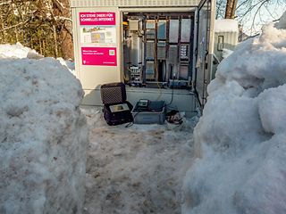 Ein Schaltschrank der Telekom im Schnee und mit offenen Türen