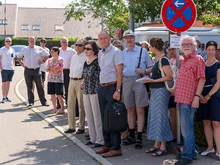 Die Bürger von Heimerdingen verfolgen mit Interesse das Geschehn, bleiben aber wegen der Hitze lieber im Schatten stehen.