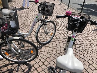 Three white bikes provided by the TelekomMobility initiative on the market place at the rail station