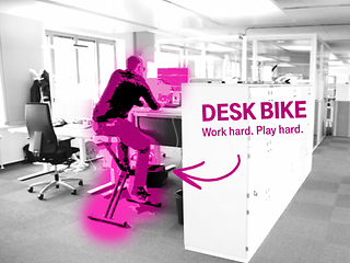 Man is sitting on a deskbike in front of the desk and is cycling